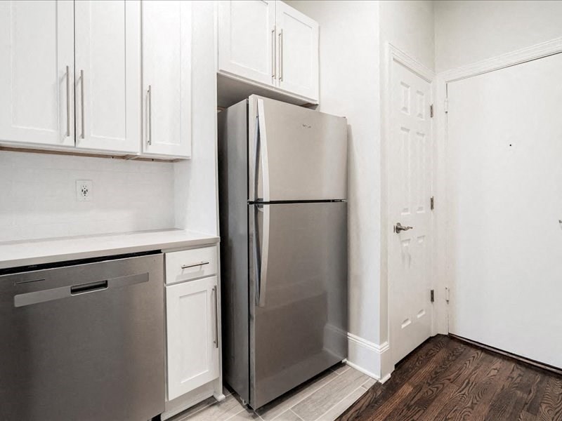 A kitchen with a refrigerator, dishwasher, and cabinets.