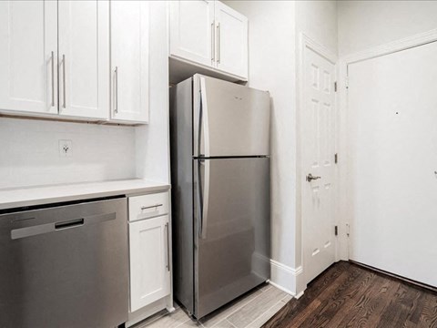 A kitchen with a refrigerator, dishwasher, and cabinets.