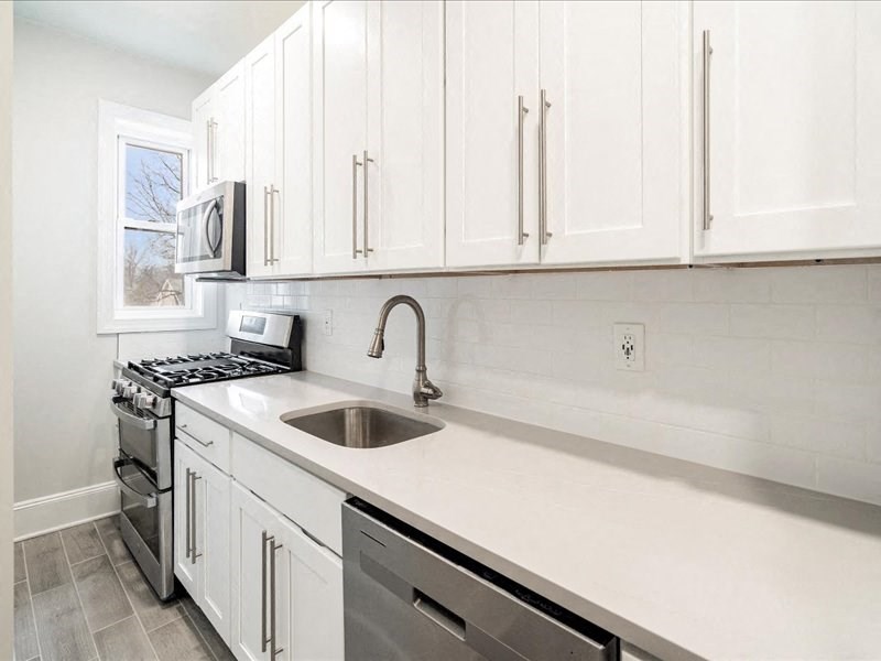 A kitchen with white cabinets and a stainless steel sink.