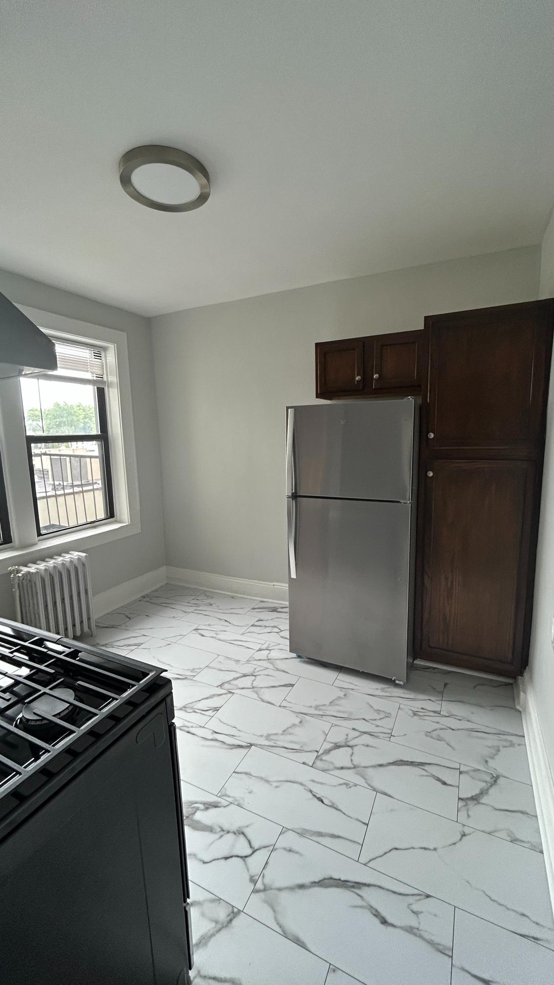 A kitchen with a marble floor and a refrigerator.