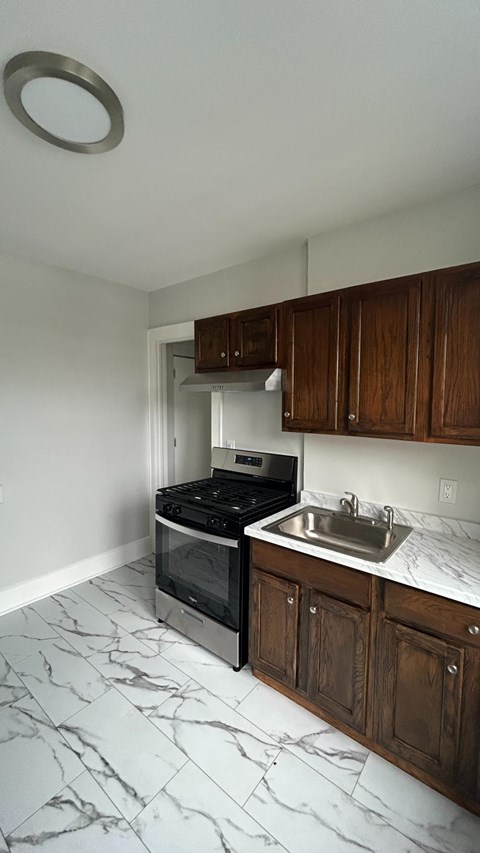 A kitchen with a black stove top oven and a white sink.