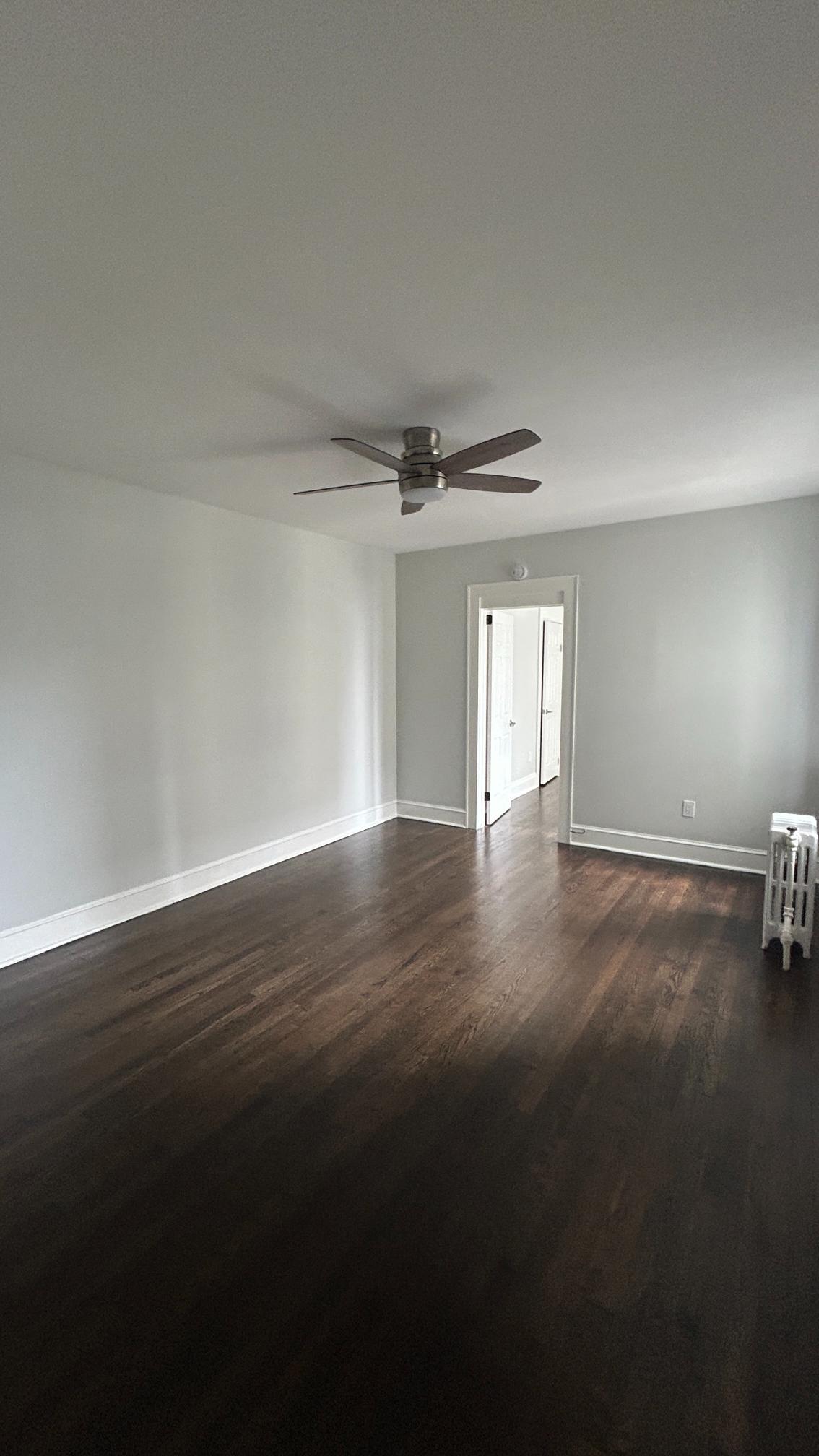 A room with a ceiling fan and a wooden floor.