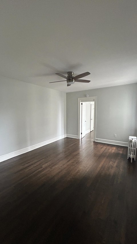 A room with a ceiling fan and a wooden floor.