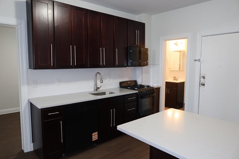 A kitchen with dark brown cabinets and white countertops.