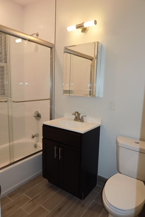 A bathroom with a toilet, sink, and mirror.