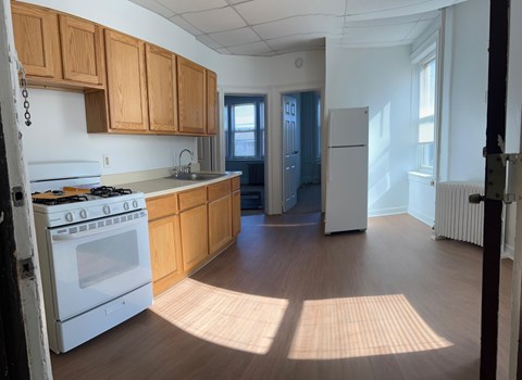 A kitchen with wooden cabinets and a white stove top oven.