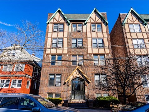 A large brick building with a green roof and a car parked in front.