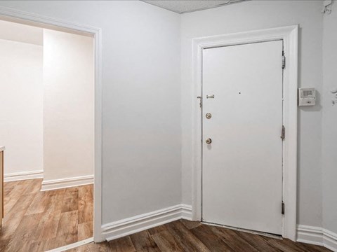 A white door is in a room with wood floors and white walls.