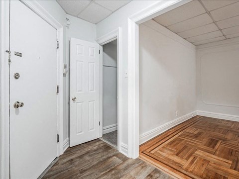 A room with a white door and a wooden floor.