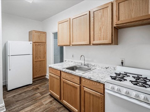 A kitchen with wooden cabinets and a white stove.