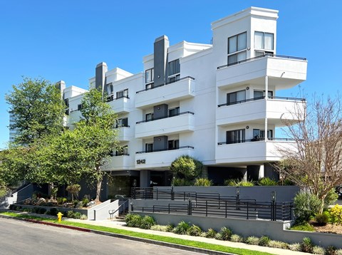 A white modern building with black railings and balconies.
