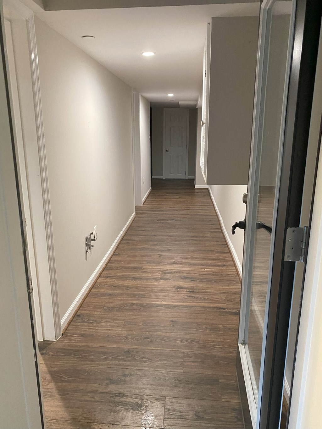 a hallway with wood floors and white walls and a door