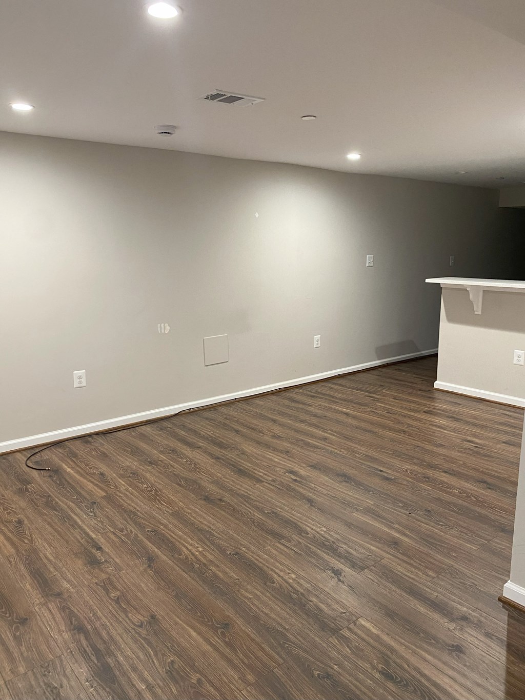 an empty living room with wood floors and white walls