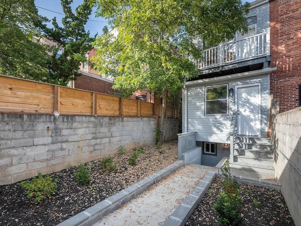 a small house with a brick wall and a wooden fence