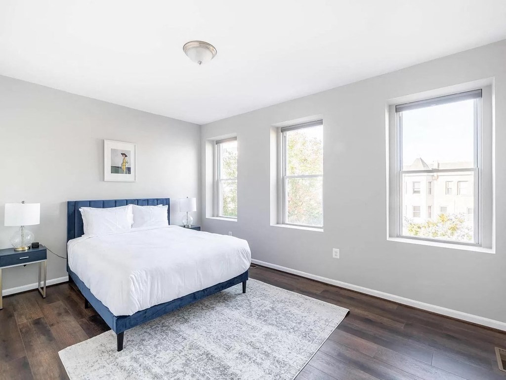 a bedroom with a bed and three windows