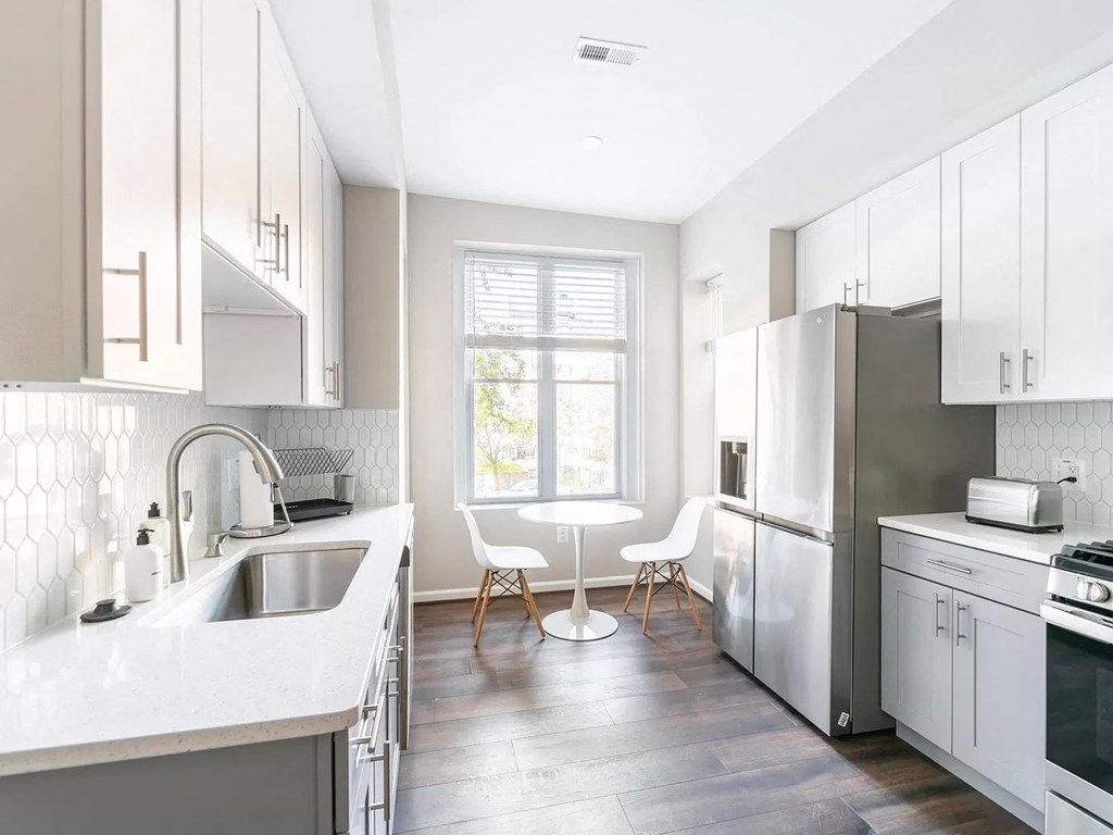 an all white kitchen with stainless steel appliances and a table