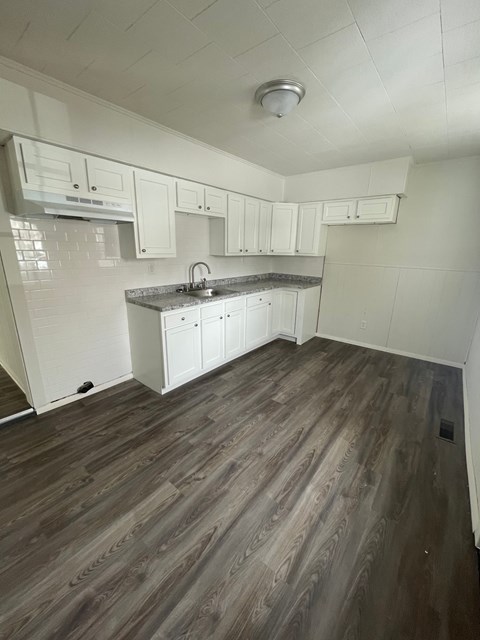 A kitchen with white cabinets and a wooden floor.