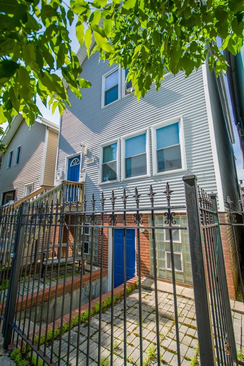 an apartment building with a yard behind a wrought iron fence