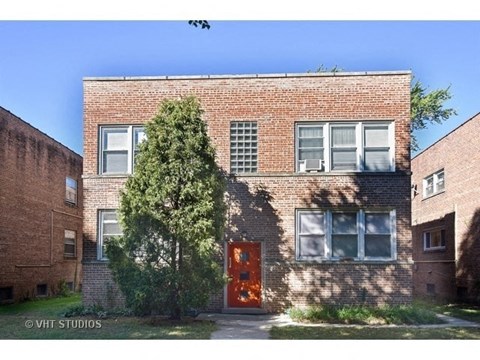 a brick building with a red door and a tree