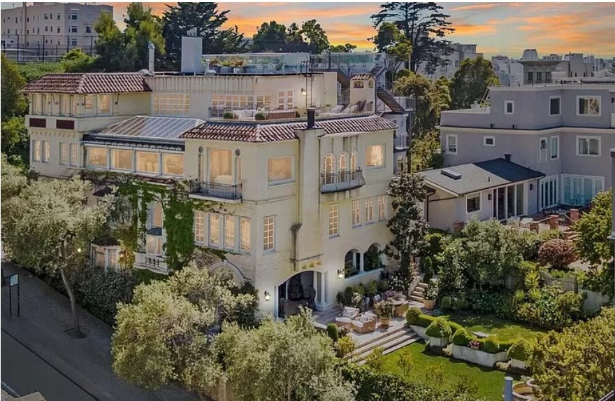 an aerial view of a mansion with trees and a street