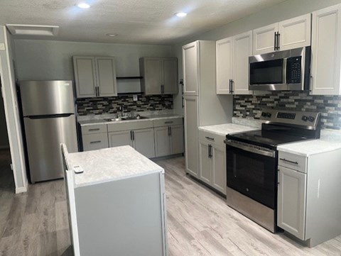 A kitchen with white cabinets and a stainless steel refrigerator.