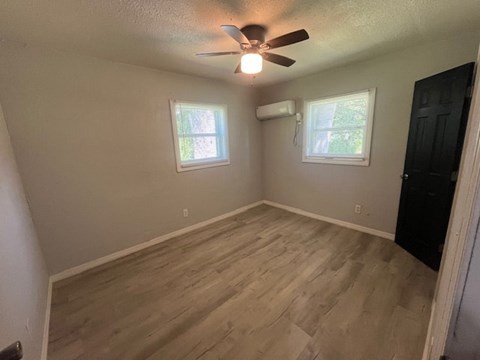 A room with a ceiling fan and two windows.