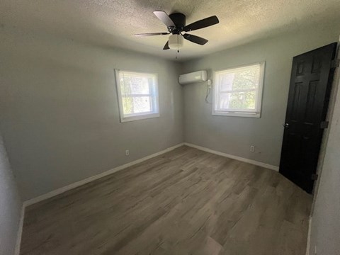A room with a ceiling fan and two windows.