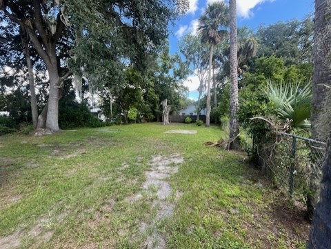 A grassy area with trees and a fence.