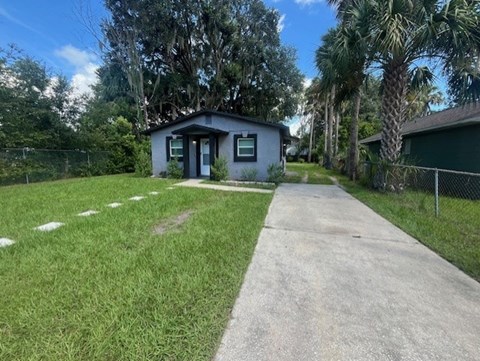 A small house with a concrete pathway leading to the front door.