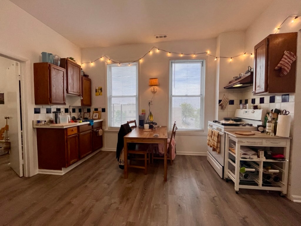 A kitchen with wooden floors and a table with chairs.