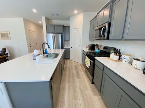 A kitchen with a white counter top and wooden floors.