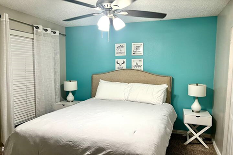 a bedroom with a white bed and a ceiling fan