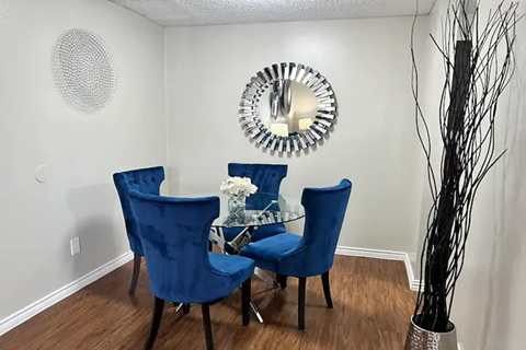 a dining room with a table and chairs and a mirror on the wall