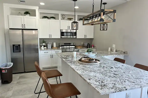 a kitchen with a marble counter top and a stainless steel refrigerator
