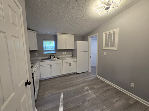 a kitchen with white cabinets and a sink and a refrigerator