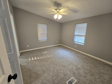 an empty living room with a ceiling fan and window