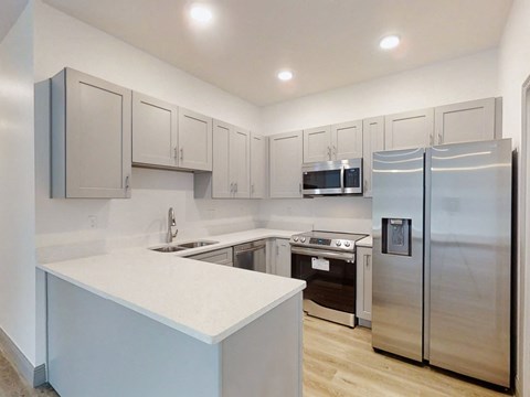 A kitchen with a white counter and stainless steel appliances.