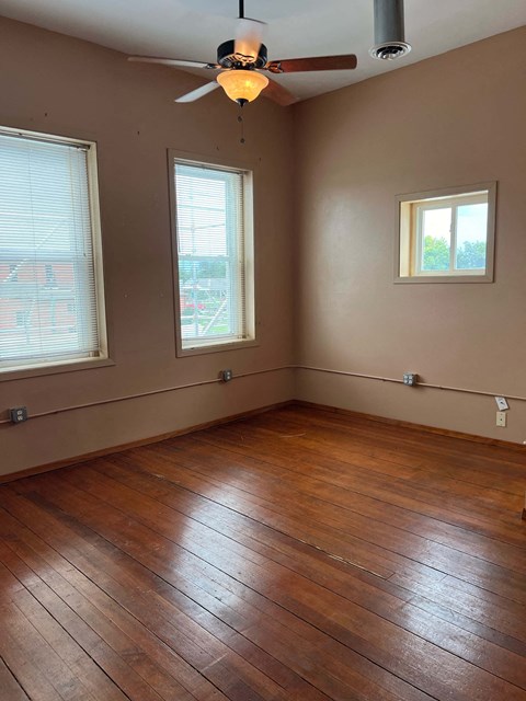 an empty living room with wooden floors and a ceiling fan