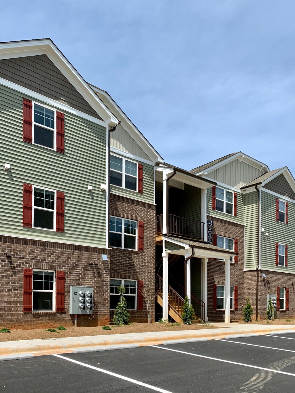 an apartment building with red doors and brick and green siding