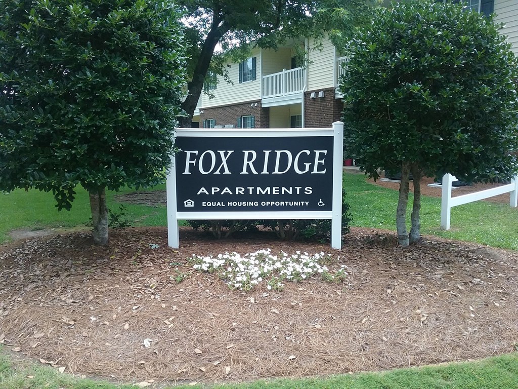a sign apartments in front of trees