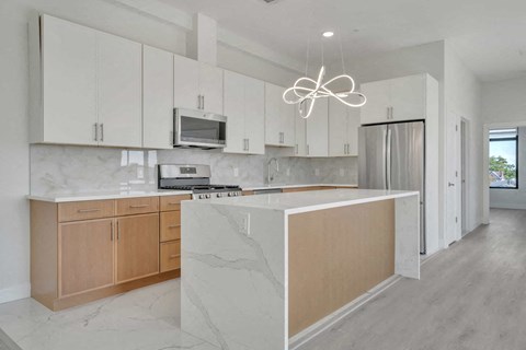 a white kitchen with wooden cabinets and a large island