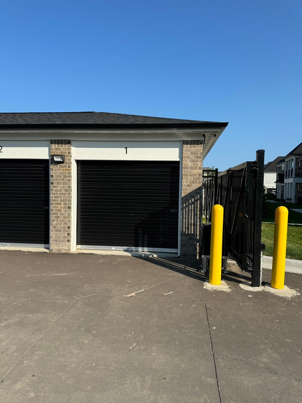 a small garage with a black gate and a fence in front of it
