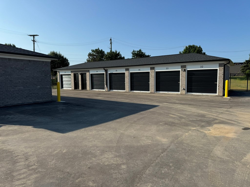 an empty parking lot in front of a building with garages