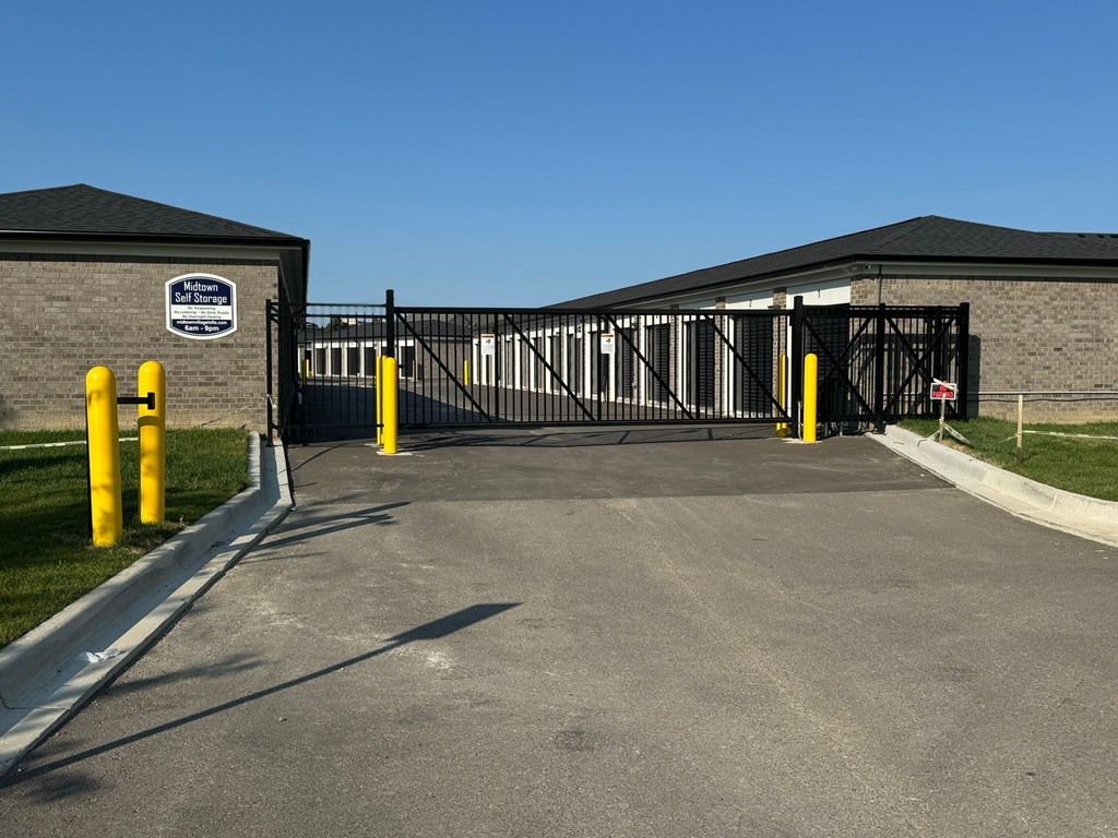 a black wrought iron gate with a stone building and a driveway