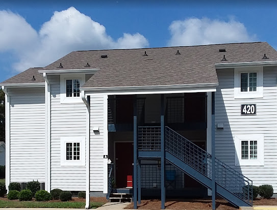a white building with stairs and a grey roof
