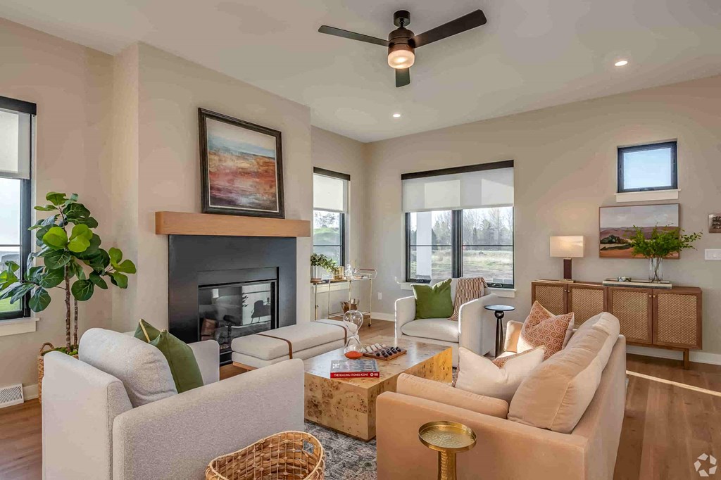 A living room with a fireplace, two couches, and a ceiling fan.