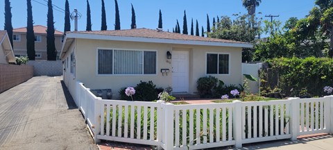 a small white house with a white fence in front of it