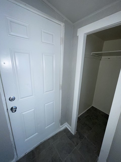 A white door with a silver handle is on the left and a white closet is on the right.