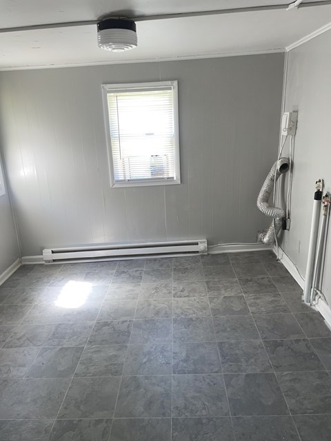 A room with a grey tile floor and a window with blinds.