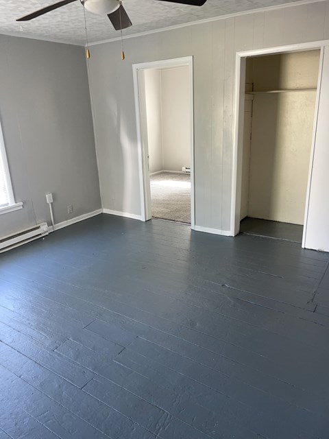 A room with a ceiling fan and two open doors.